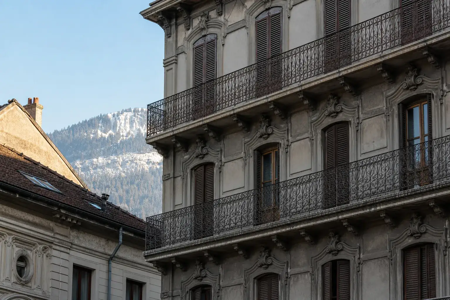 Façade d’immeuble de rapport grenoblois en ciment moulé, balcons filants et fenêtres alignées