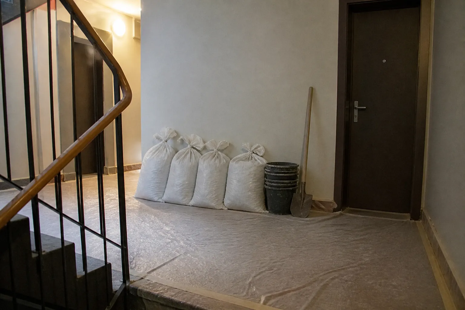 Sacs de gravats alignés sur un palier protégé, prêts à descendre