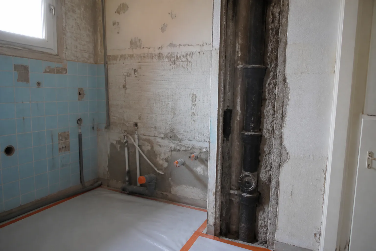 Salle de bain démolie laissant voir le raccordement à la colonne d’évacuation commune